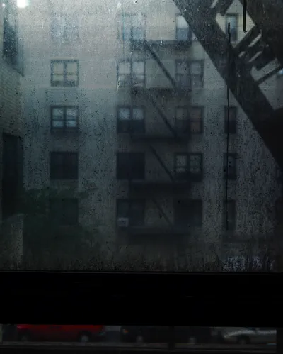 Long-exposure scanning-back photograph of an apartment building facade seen through a grime-covered window, image 6 of 8 in the Grid Dirt Glass series.