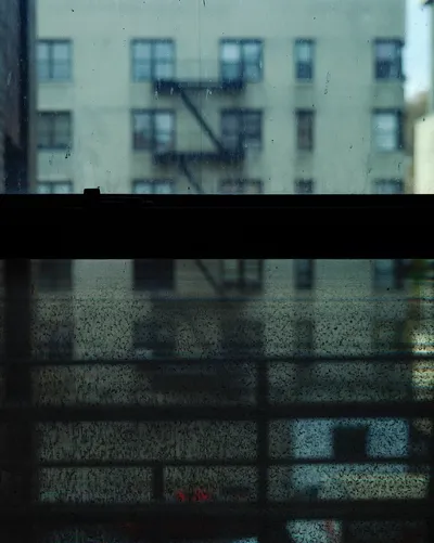 Long-exposure scanning-back photograph of an apartment building facade seen through a grime-covered window, image 7 of 8 in the Grid Dirt Glass series.