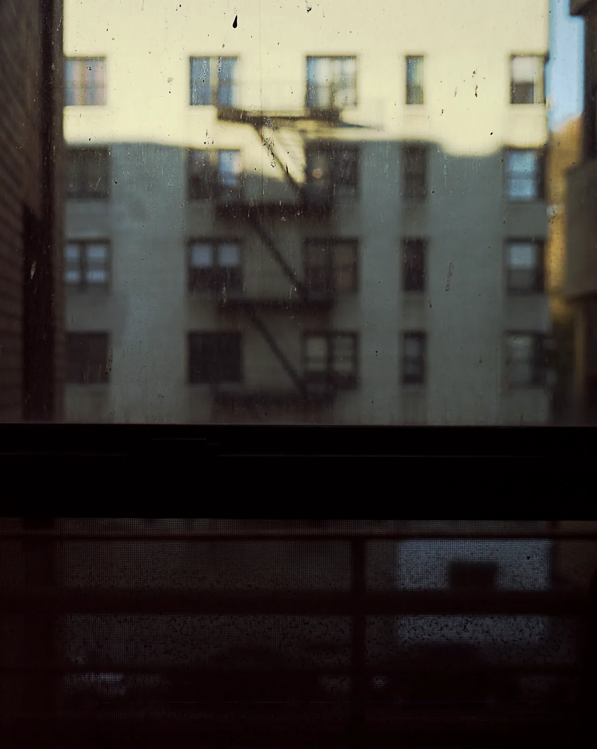 Long-exposure scanning-back photograph of an apartment building facade seen through a grime-covered window, image 8 of 8 in the Grid Dirt Glass series.