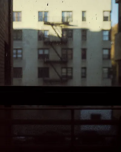 Long-exposure scanning-back photograph of an apartment building facade seen through a grime-covered window, image 8 of 8 in the Grid Dirt Glass series.